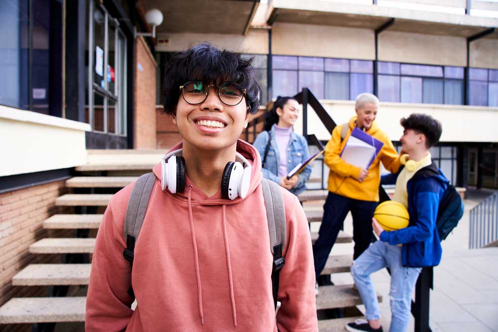 Smiling student outside of university wearing headphones