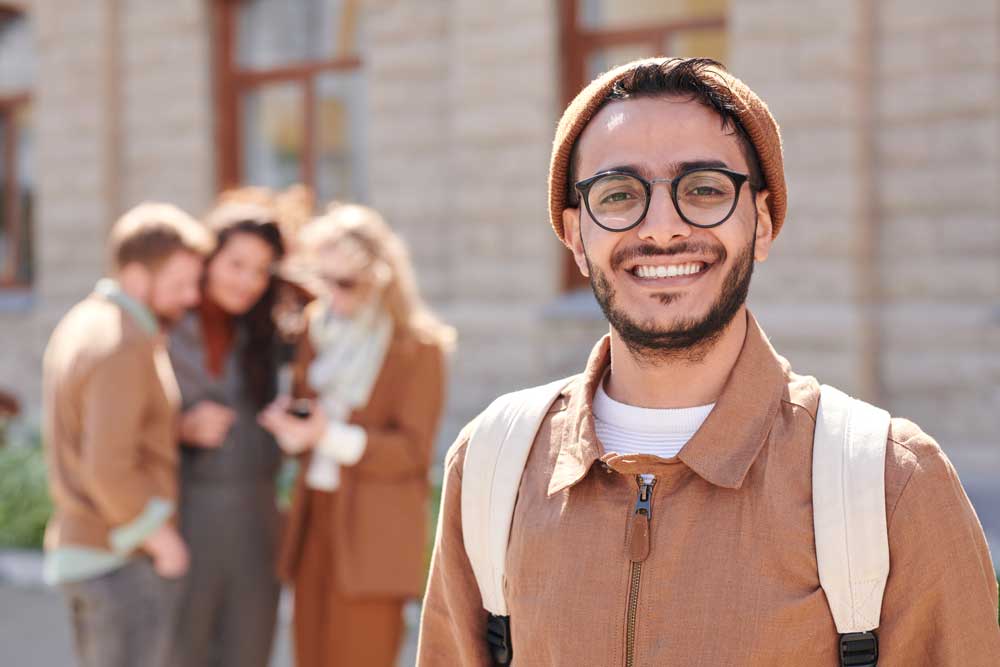 Smiling male student near university building